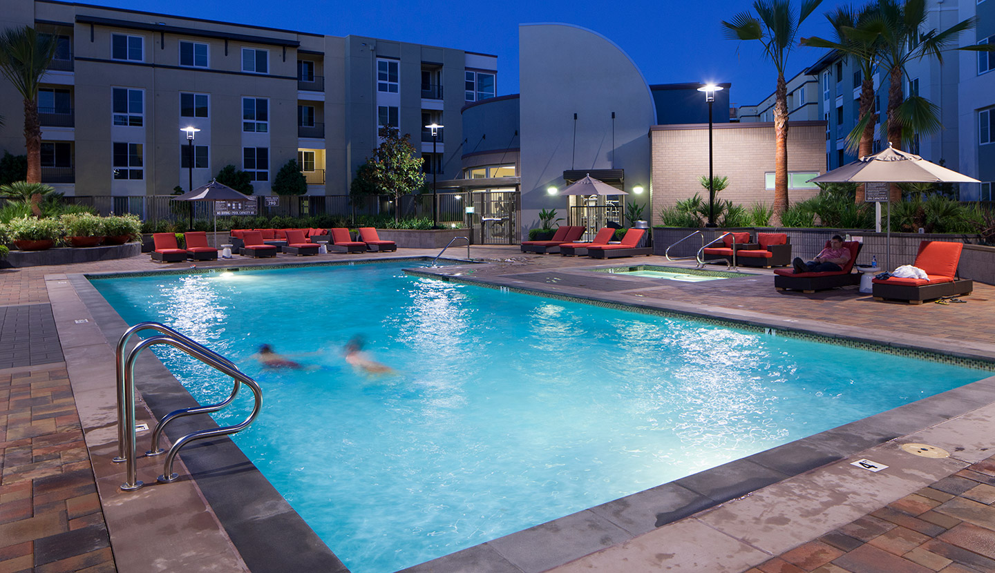 Evening shot of the pool with two people swimming at the apartment complex